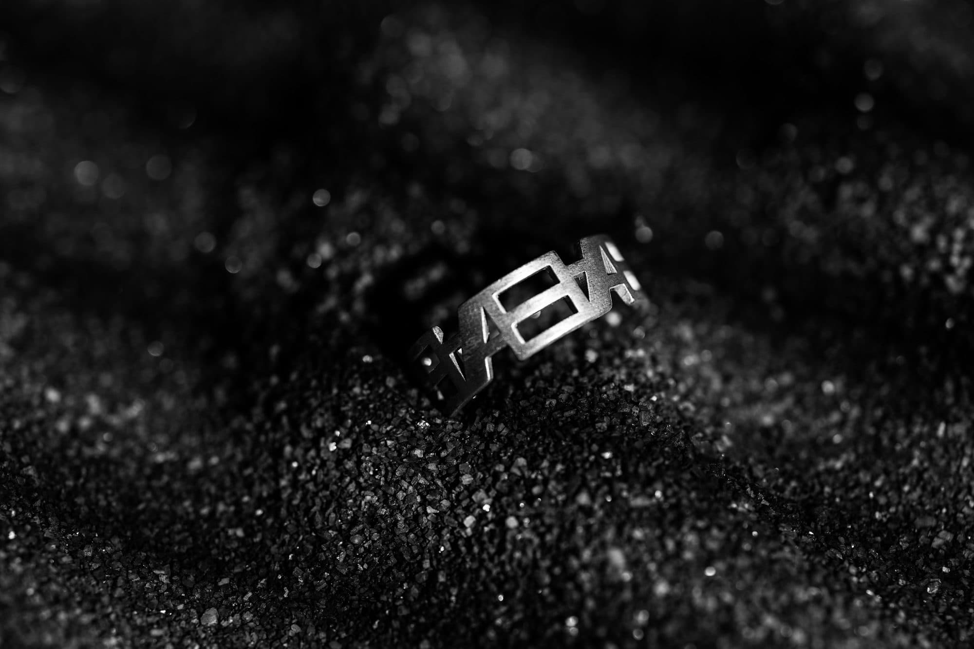 Inverted Monogram ring resting in black sand